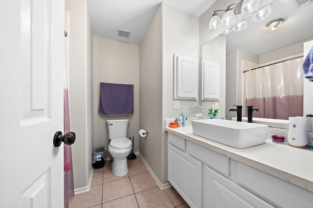 bathroom with a textured ceiling, toilet, vanity, baseboards, and tile patterned floors