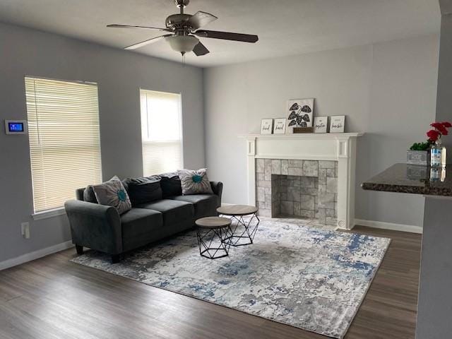 living area with a ceiling fan, dark wood-style flooring, baseboards, and a tiled fireplace