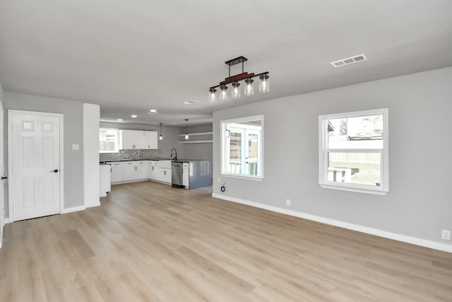 unfurnished living room with baseboards, visible vents, light wood-type flooring, a sink, and recessed lighting