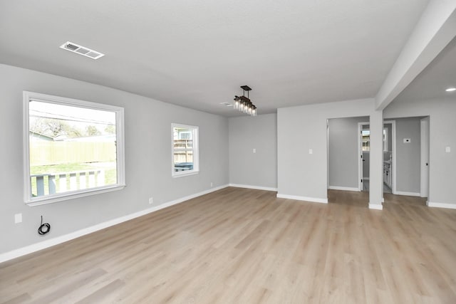 unfurnished room with light wood-style floors, visible vents, and baseboards