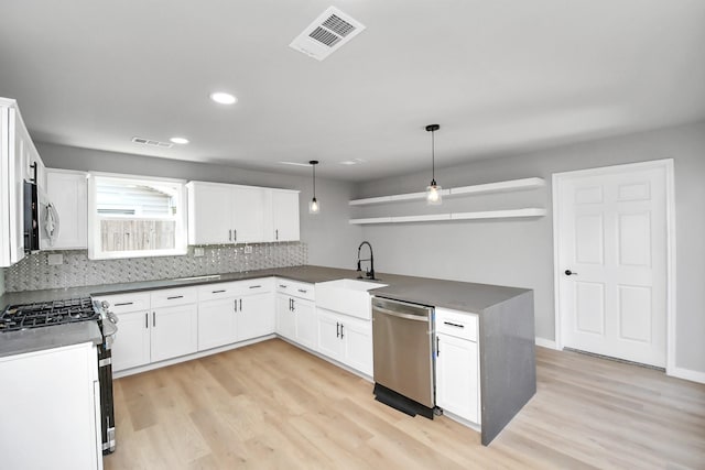 kitchen with stainless steel appliances, dark countertops, visible vents, and a sink