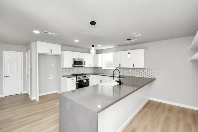 kitchen featuring a peninsula, a sink, visible vents, appliances with stainless steel finishes, and tasteful backsplash