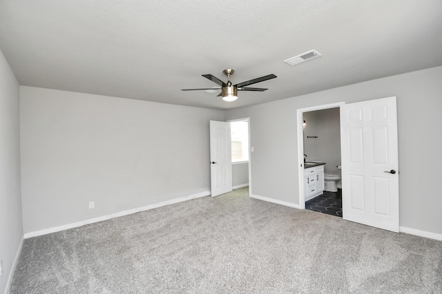 unfurnished bedroom with carpet floors, visible vents, connected bathroom, a textured ceiling, and baseboards