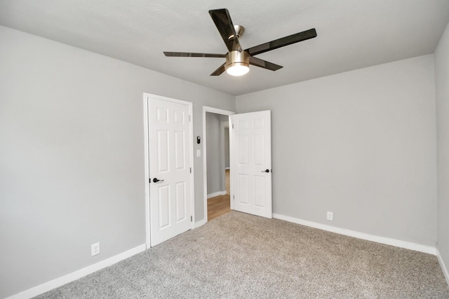 carpeted empty room featuring baseboards and a ceiling fan