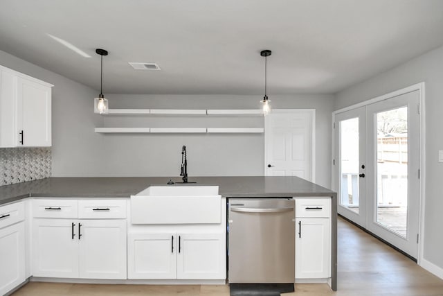 kitchen with a sink, visible vents, white cabinetry, stainless steel dishwasher, and dark countertops