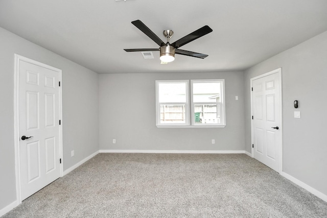 unfurnished room with carpet floors, visible vents, baseboards, and a ceiling fan