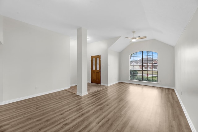 interior space with a ceiling fan, lofted ceiling, baseboards, and wood finished floors