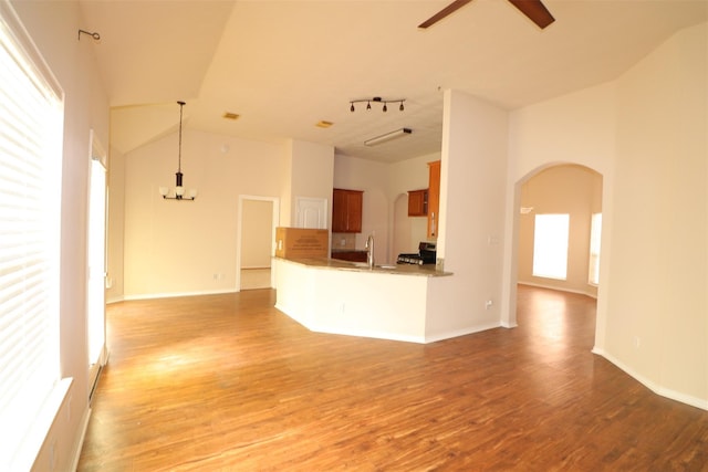 interior space with arched walkways, open floor plan, light wood-type flooring, and a ceiling fan