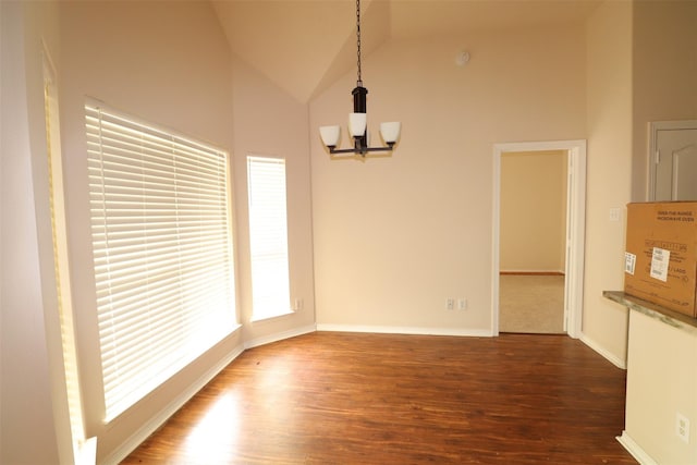 unfurnished dining area featuring high vaulted ceiling, wood finished floors, baseboards, and an inviting chandelier