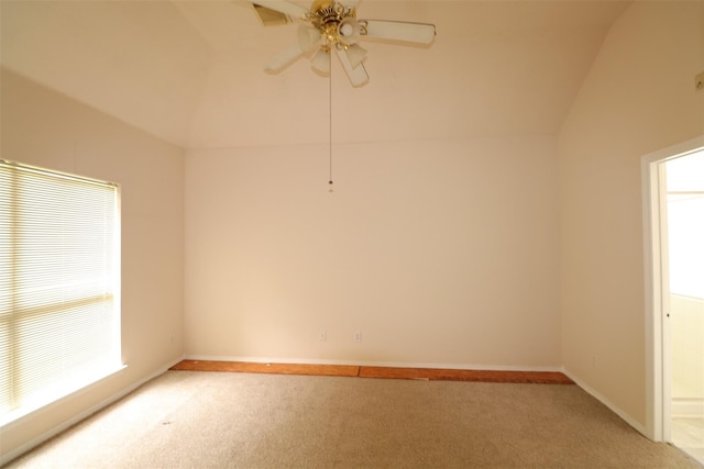 empty room featuring lofted ceiling, visible vents, light carpet, ceiling fan, and baseboards