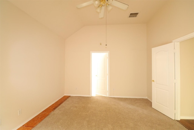 carpeted spare room with ceiling fan, visible vents, vaulted ceiling, and baseboards