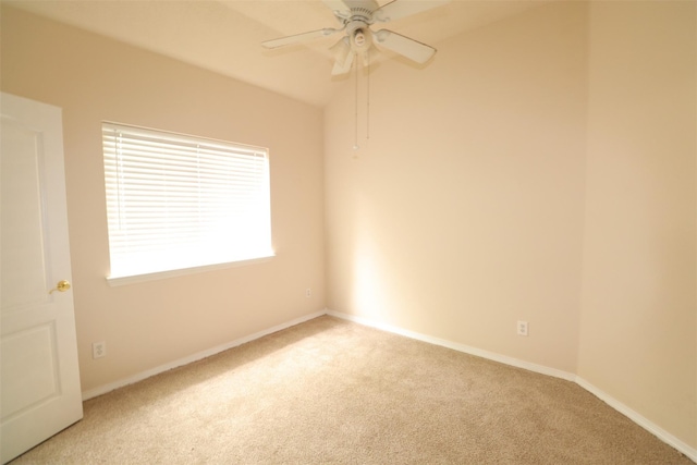 spare room featuring light colored carpet, ceiling fan, and baseboards