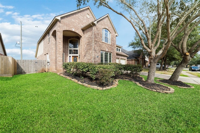 view of front facade with a front yard, fence, and brick siding