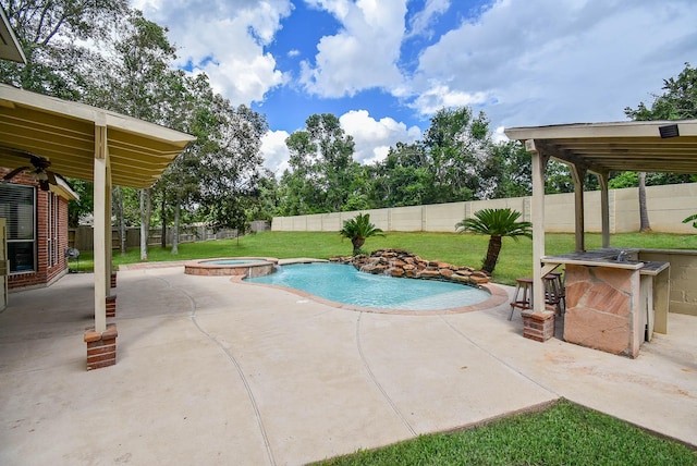 view of swimming pool with a bar, a patio area, a fenced backyard, and a pool with connected hot tub