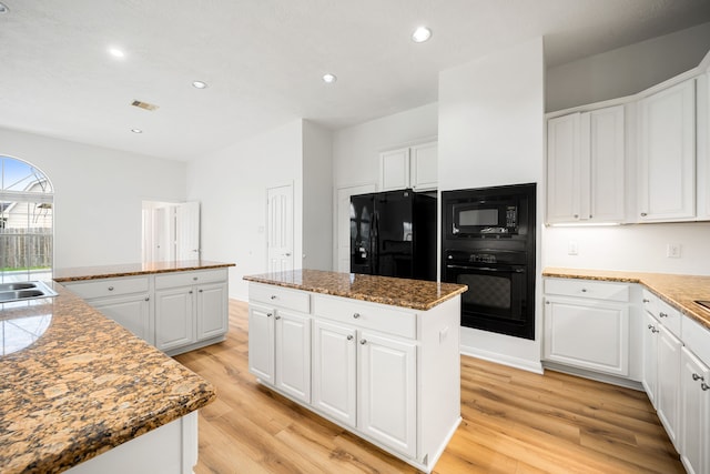 kitchen with visible vents, white cabinets, a center island, black appliances, and light wood finished floors