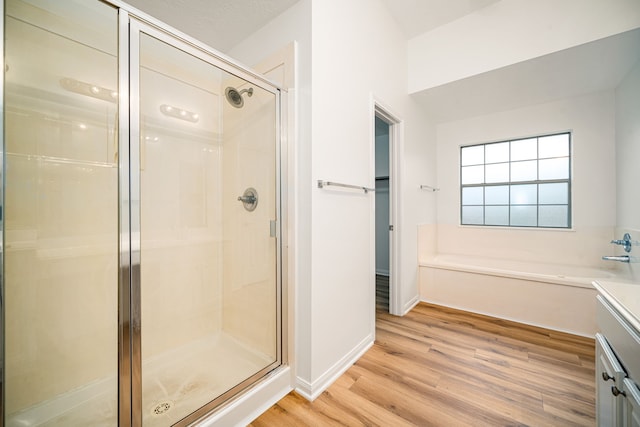 full bathroom featuring a stall shower, a garden tub, baseboards, and wood finished floors