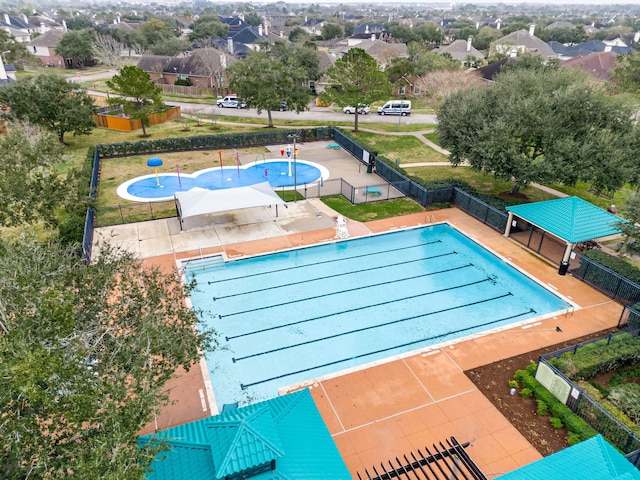 community pool with a residential view, a patio area, fence, and a lawn