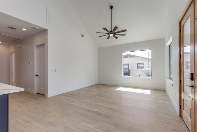 unfurnished living room with light wood finished floors, visible vents, baseboards, ceiling fan, and high vaulted ceiling