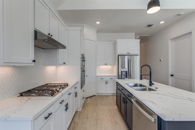 kitchen with a center island with sink, visible vents, a sink, stainless steel appliances, and under cabinet range hood