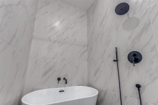 bathroom featuring a marble finish shower, tile walls, and a freestanding tub