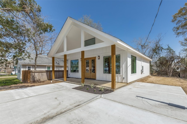 exterior space featuring french doors, board and batten siding, and fence