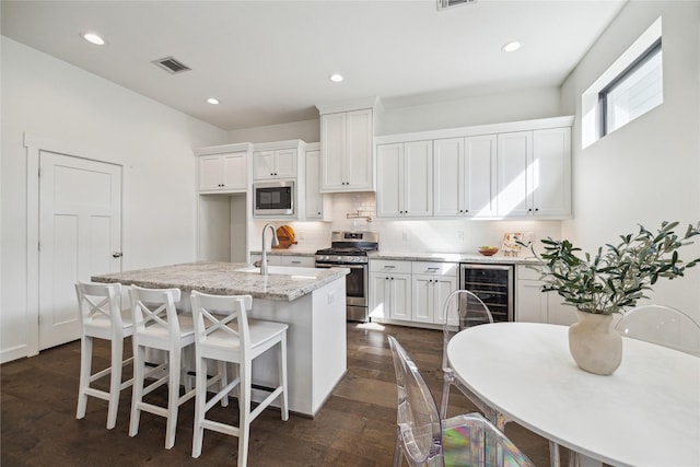 kitchen featuring visible vents, decorative backsplash, a sink, built in microwave, and gas range