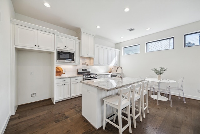 kitchen with decorative backsplash, white cabinets, dark wood-style floors, and appliances with stainless steel finishes