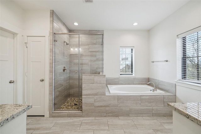 full bath with vanity, a garden tub, plenty of natural light, and a stall shower