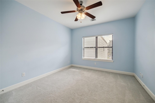 spare room with visible vents, baseboards, light colored carpet, and a ceiling fan