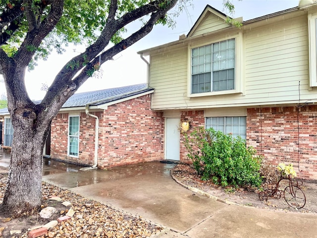 view of front of house featuring a patio and brick siding