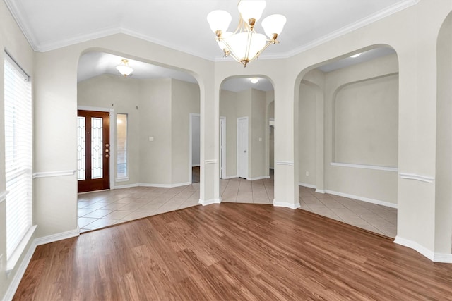 interior space featuring a chandelier, ornamental molding, vaulted ceiling, and baseboards