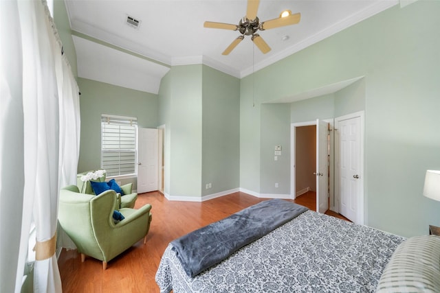 bedroom featuring visible vents, ornamental molding, a ceiling fan, wood finished floors, and baseboards