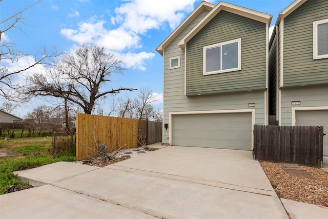 view of home's exterior featuring a garage, driveway, and fence