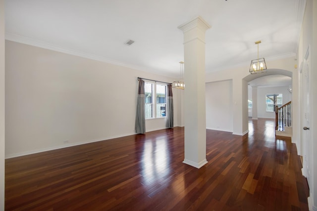 unfurnished room with dark wood-style floors, arched walkways, decorative columns, crown molding, and visible vents