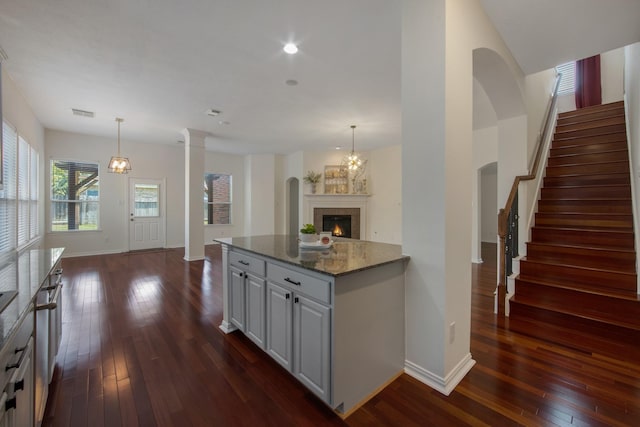 kitchen featuring stone countertops, open floor plan, dark wood-style flooring, and decorative light fixtures