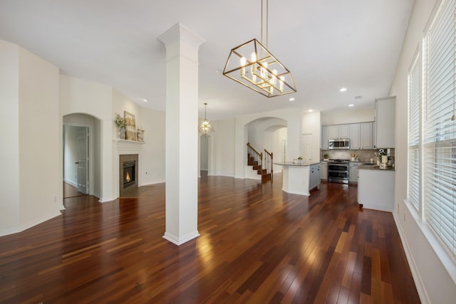 living room featuring baseboards, dark wood-style flooring, a fireplace, a chandelier, and recessed lighting