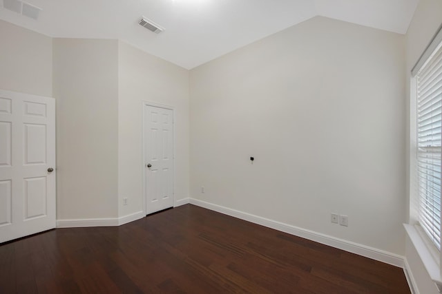 unfurnished room featuring baseboards, visible vents, vaulted ceiling, and dark wood-type flooring