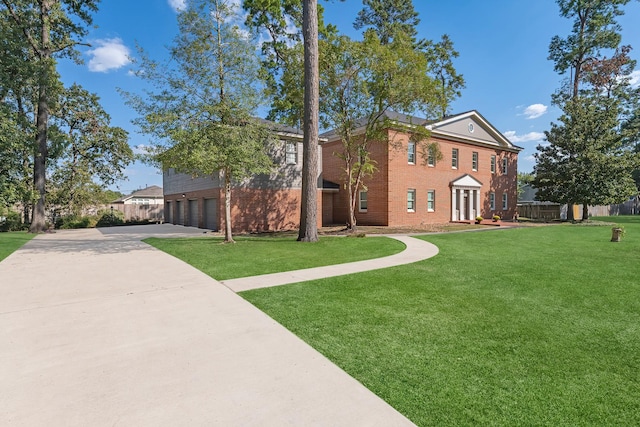 view of front of home with concrete driveway, brick siding, a front lawn, and an attached garage