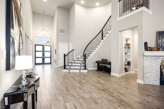 entryway with baseboards, visible vents, wood finished floors, stairs, and french doors