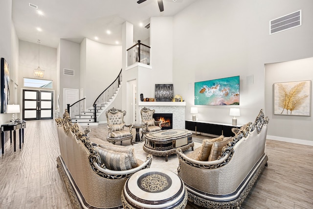 living area with stairs, a tiled fireplace, wood finished floors, and visible vents