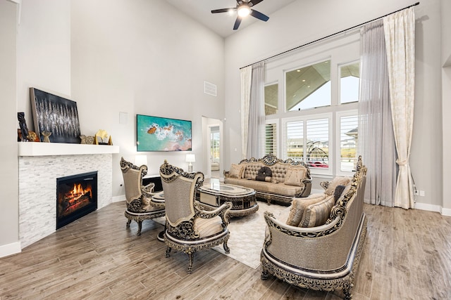 living room with high vaulted ceiling, wood finished floors, visible vents, baseboards, and a glass covered fireplace