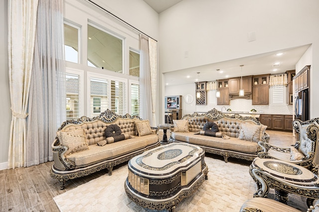 living room with light wood-type flooring, a high ceiling, and recessed lighting