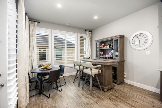 dining area with a dry bar, recessed lighting, wood finished floors, and baseboards