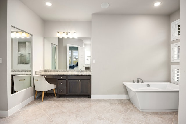 bathroom featuring a freestanding tub, a healthy amount of sunlight, vanity, and baseboards