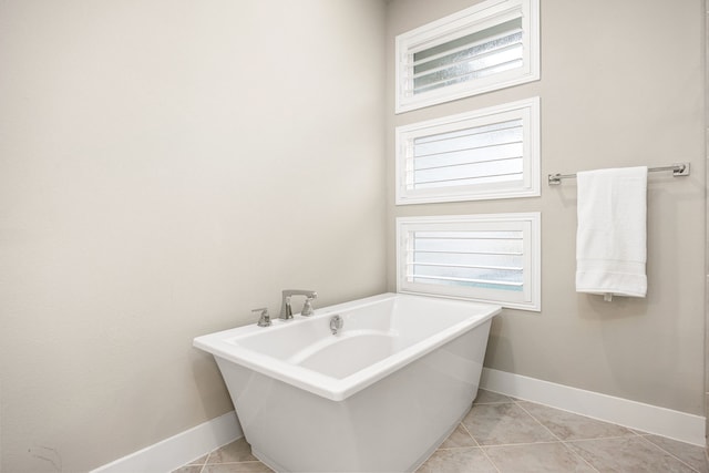 bathroom featuring tile patterned flooring, a freestanding tub, and baseboards