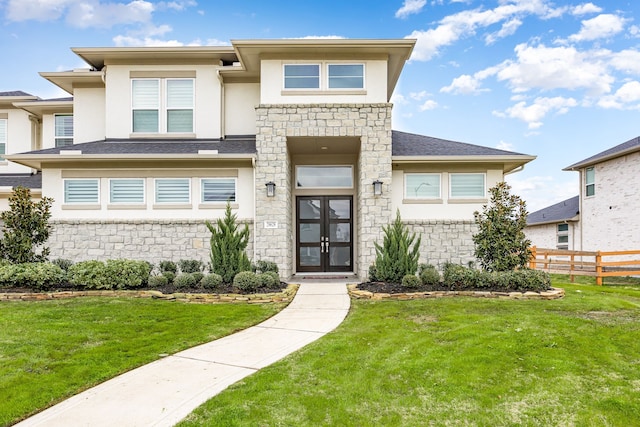 prairie-style home with stone siding, a front lawn, fence, and stucco siding