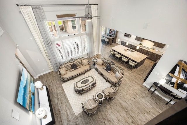 living area with ceiling fan, wood finished floors, and baseboards