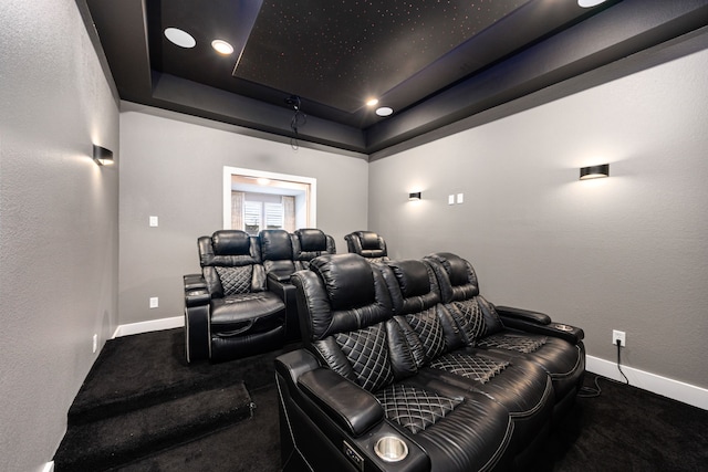 cinema room featuring a tray ceiling, carpet flooring, and baseboards