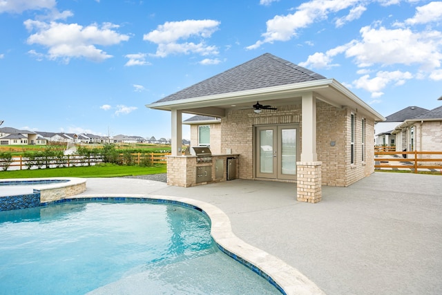 view of pool with a patio, area for grilling, an outdoor kitchen, a ceiling fan, and a residential view