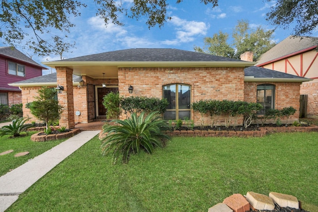 view of front of house with a front lawn, a chimney, a shingled roof, and brick siding